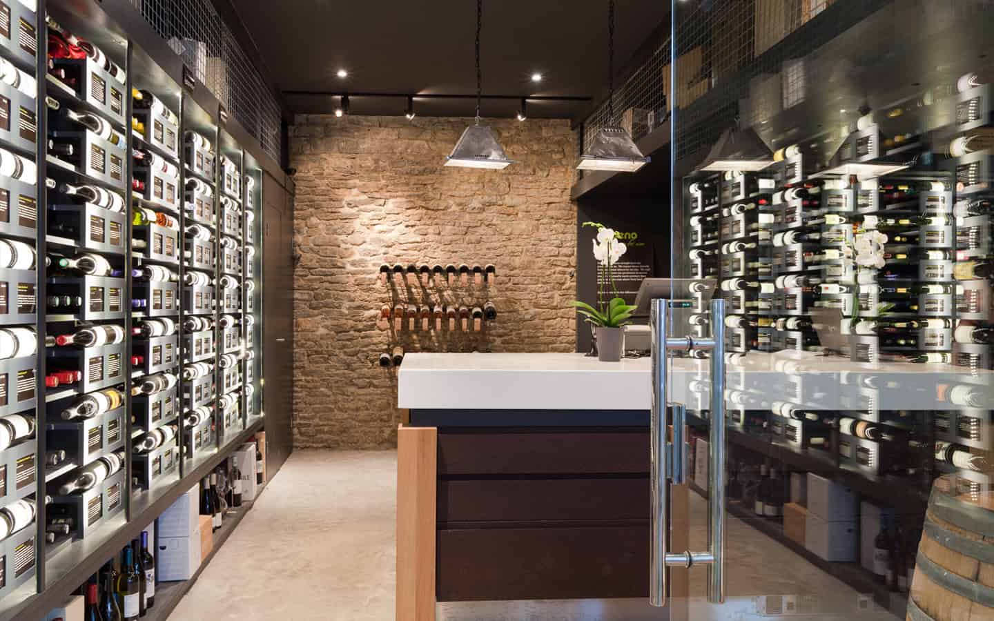 Oeno Wines shop interior with bespoke metal wine racking, exposed stone wall, and pendant lighting